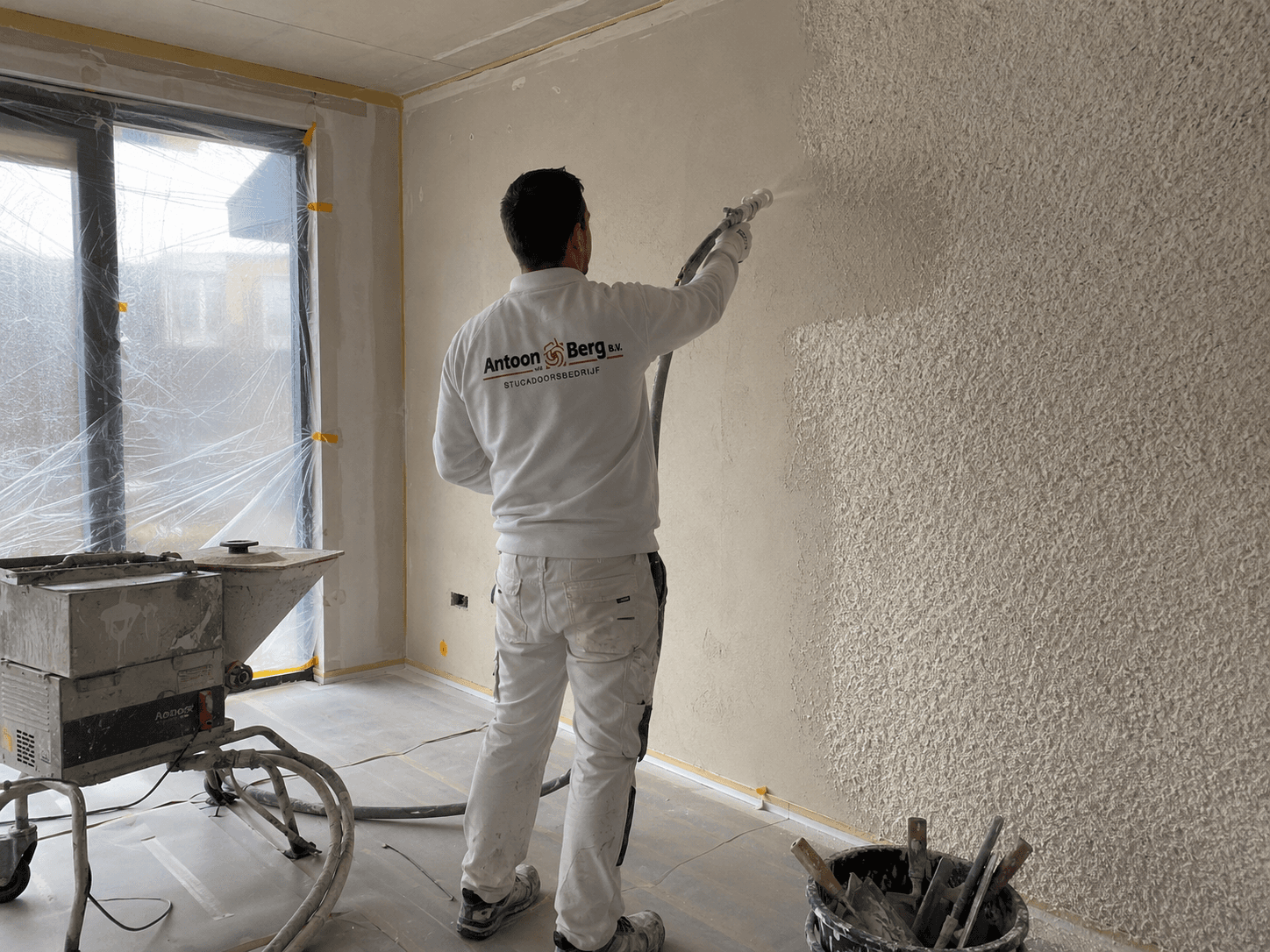 Vakman voert gips spuitwerk uit op wand of plafond
